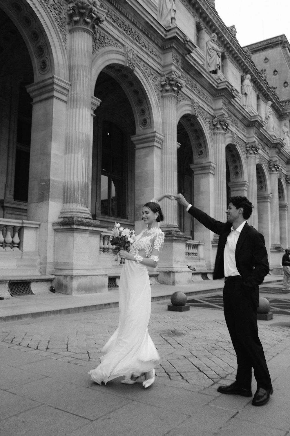 Matiné fotografija: jaunieji sukasi susikibę rankomis prie Paryžiaus rūmų